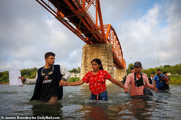 Migrants wade through the waters of the Rio Grande to cross into the US, where they will be met with no opposition, processed, and sent to a new US city