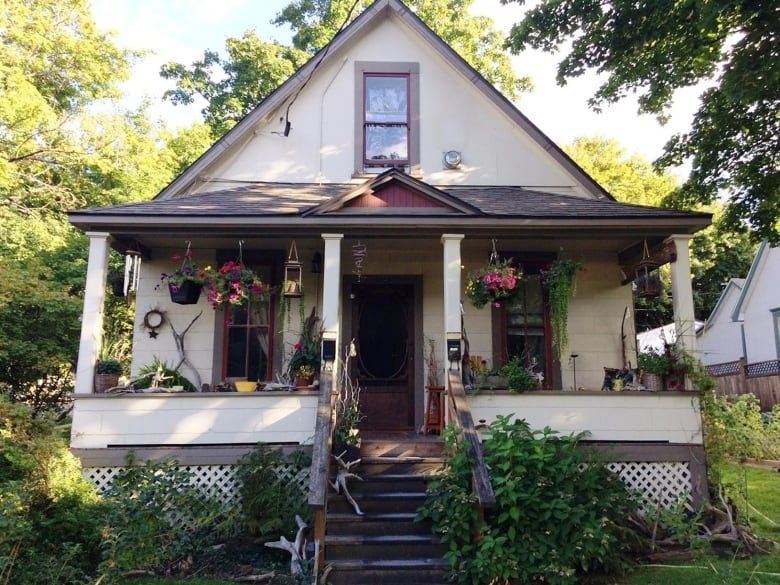 The front entrance of a home with a garden full of plant bushes and flower pots. 