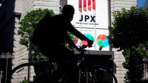 A cyclist passes the Tokyo Stock Exchange