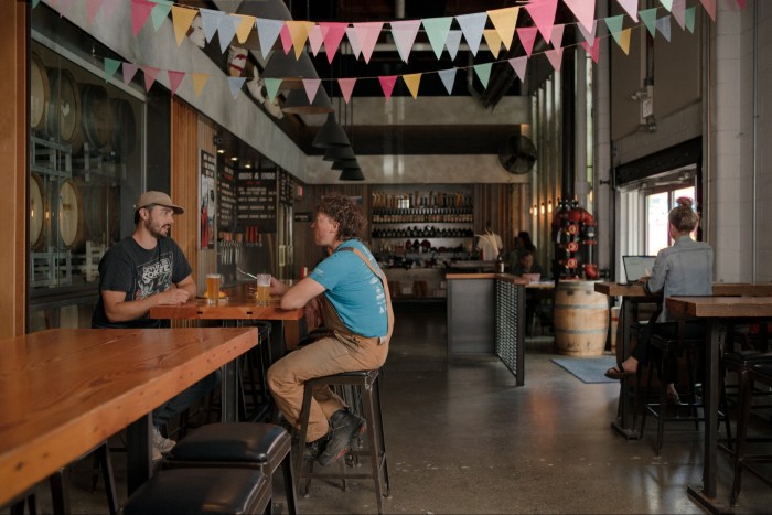 Customers at tables in Strange Fellows’ wood and stainless-steel tasting room