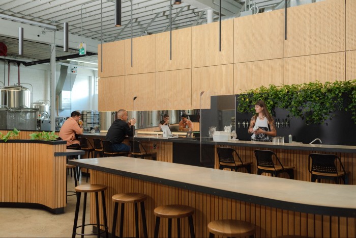 Guests sitting at the blond-wood Scandi-style bar in Superflux