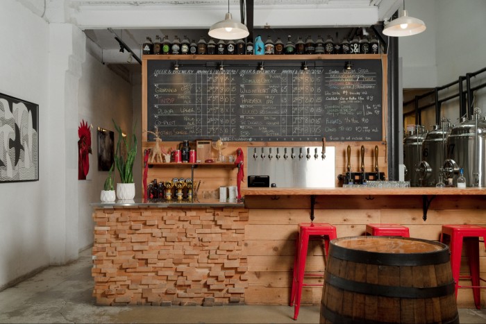 Callister’s wood and brickwork bar, with red stools and a wooden cask in front of it