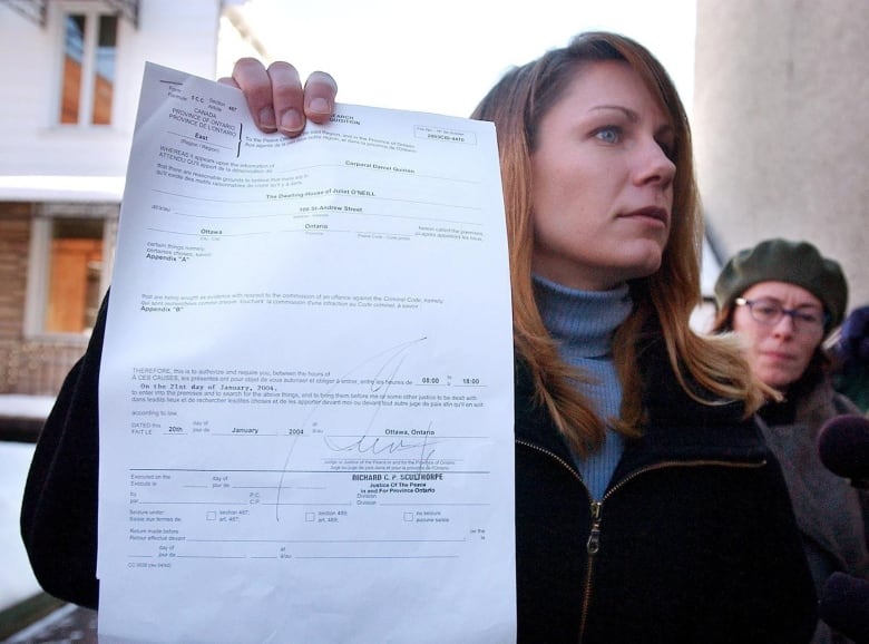 Ottawa Citizen newspaper lawyer Wendy Montgomery holds up a search warrant as Citizen reporter Juliet O'Neill (right) looks on in front of O'Neill's house in Ottawa, Wednesday, Jan.21, 2004. RCMP officers searched the home and office of O'Neill Wednesday seeking the source of an alleged information leak in the case of Maher Arar. 