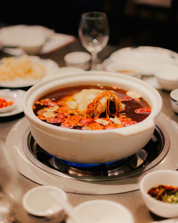 One of Landmark’s hotpots in a round white dish sitting on a burner on a table set with plates and bowls