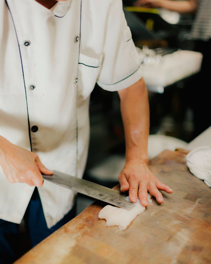 Chef David Li slicing fish on a counter at Landmark Hotpot House 