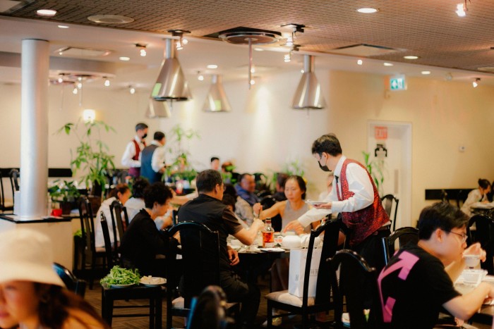 Guests at tables in the dining room at Landmark being served by waiters