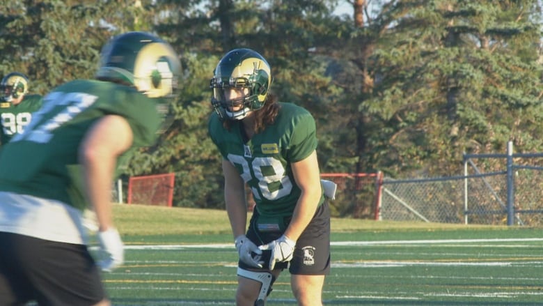 A football player in a green jersey and a green helmet playing. 