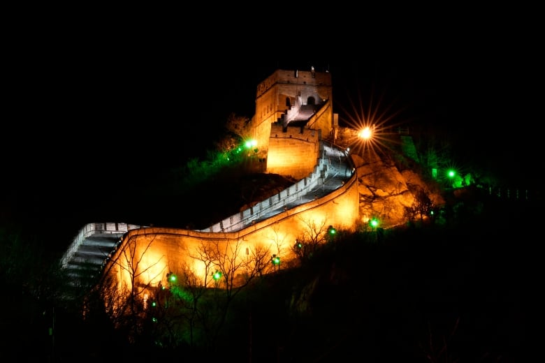 A wide, walled staircase up a hillside is illuminated at night.