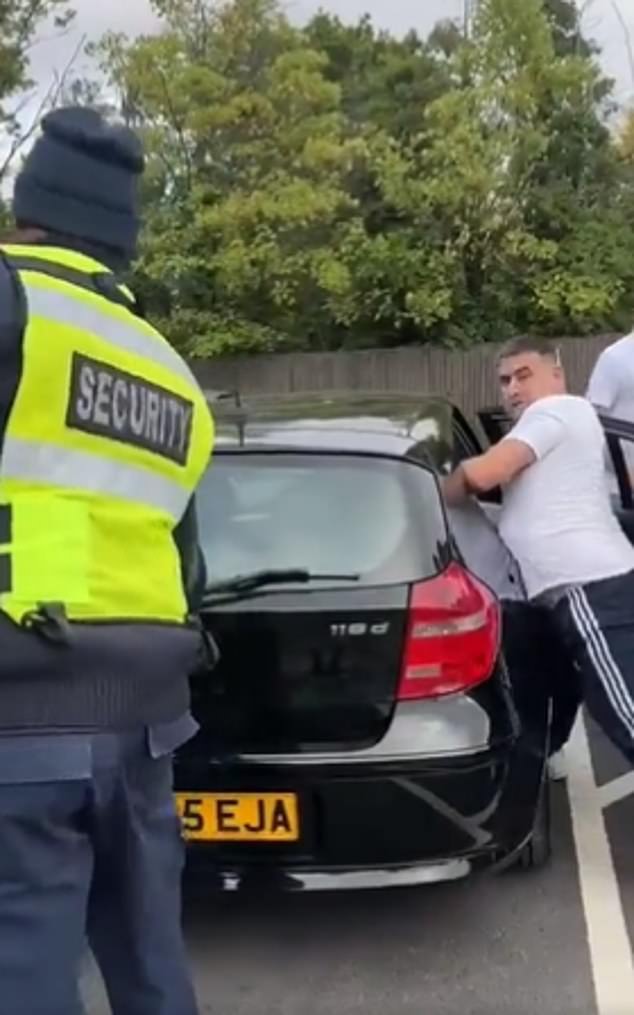 A security guard (pictured) can be seen trying to open the boot of the car to get to the allegedly stolen goods