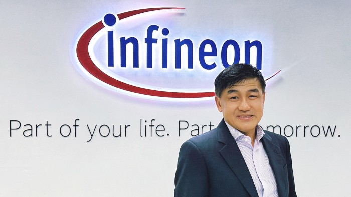 Ng Kok Tiong posing in front of the Infineon logo