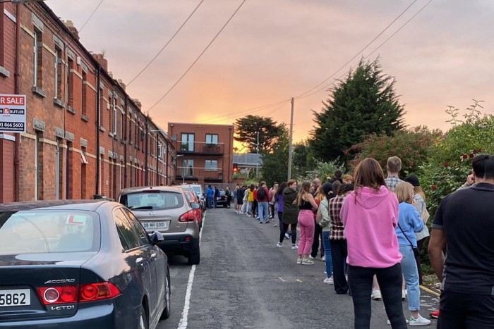 A long queue stretching down the road of people waiting to view a house