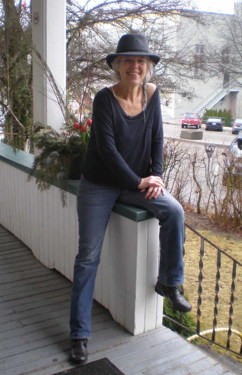 A smiling woman with a braid sitting on a porch. 