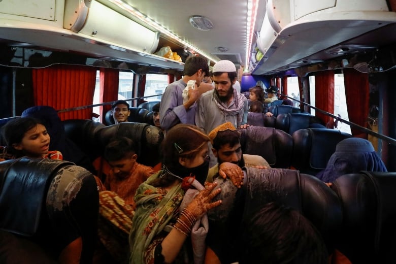 Migrants get on a bus. 