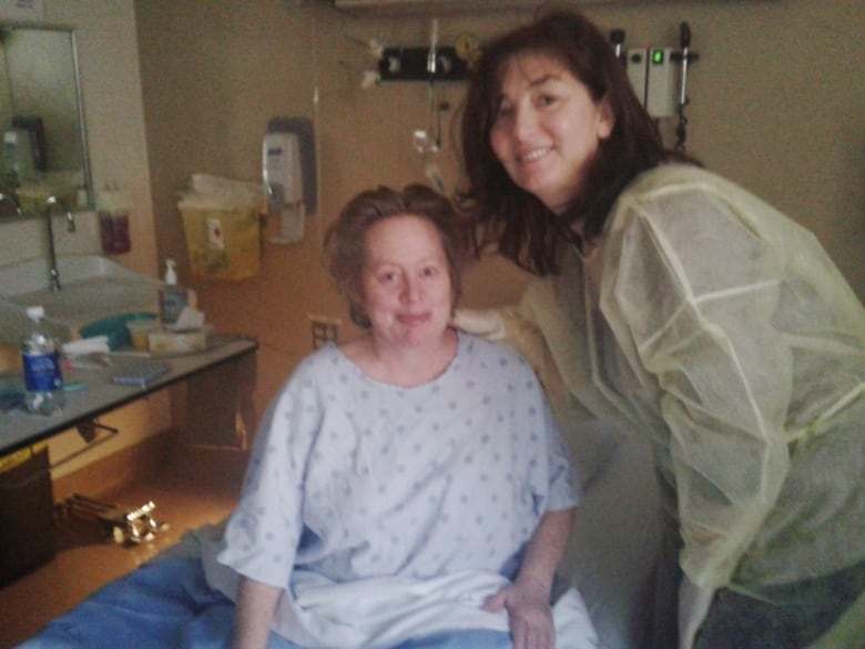 Sheila Crotty laying in a hospital bed, posing with her nurse.