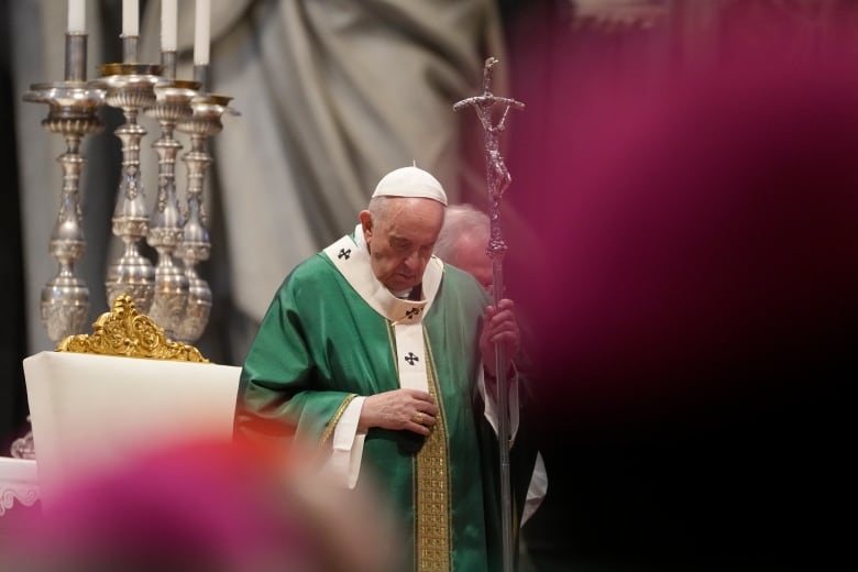 The Pope, wearing a green and white robe, holds a pastoral staff.