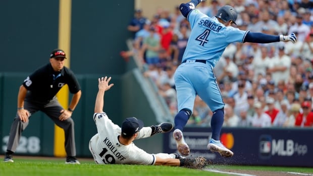 A baseball player jumps over another who is sliding on the ground.