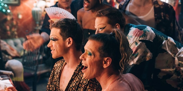 Still frame from the film Solo. Drag queens laugh together.