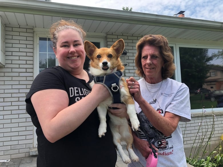 smiling mom and daughter with happy corgi