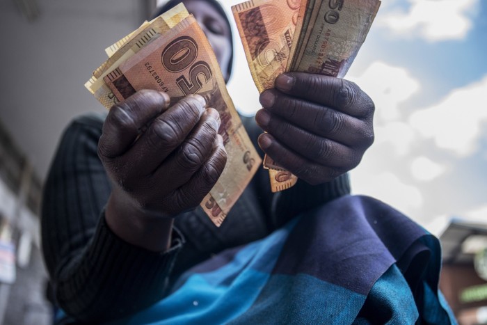 A street vendor counts Zimbabwean banknotes