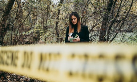 Young female inspector or investigator collecting evidence and taking notes about crime scene in the forest.