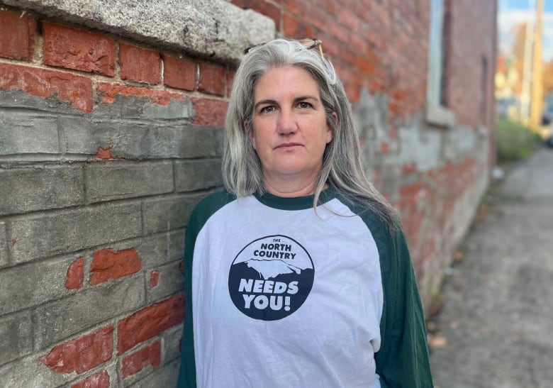 Woman in  T shirt standing next to brick wall