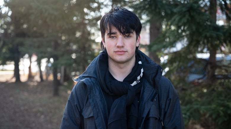 Spencer Hudson, a student in Ottawa stands looking forward outside in a park.