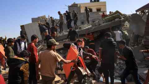 A Palestinian medic carries a stretcher as he walks among civilians on the rubble of a building after an air strike on Rafah