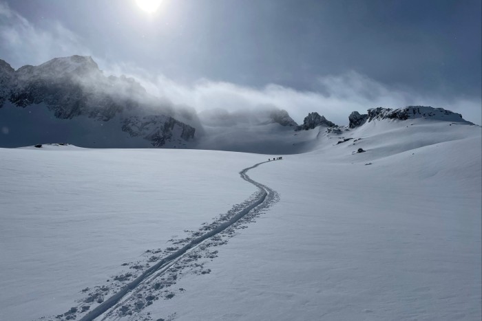 A trail in an expanse of snow heads into the distance