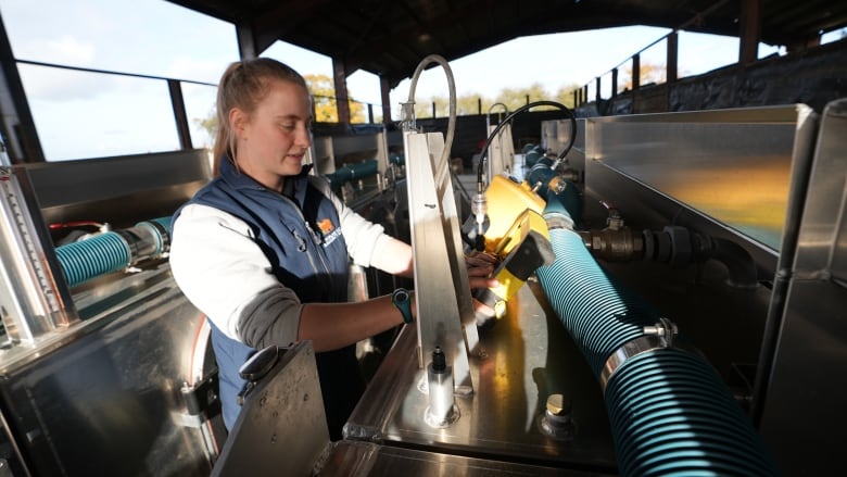 A woman works with some machinery.