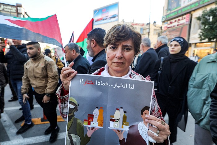 A woman holds a sign calling for the boycott of Israeli products during a demonstration in Ramallah on Boxing Day