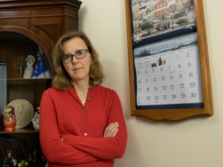 A woman stands next to a calendar.