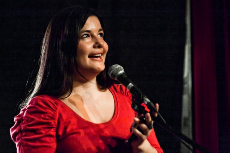 A woman looks upward while holding a microphone.