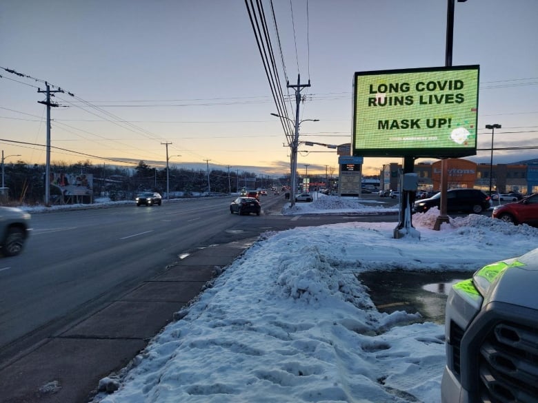 A sign along a road that says "Long covid ruins lives. Mask up"