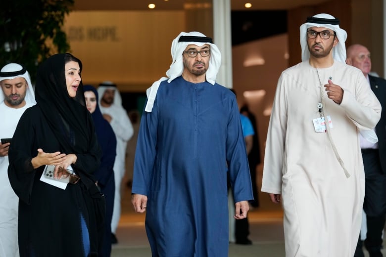 Three people talk as they walk at a conference.