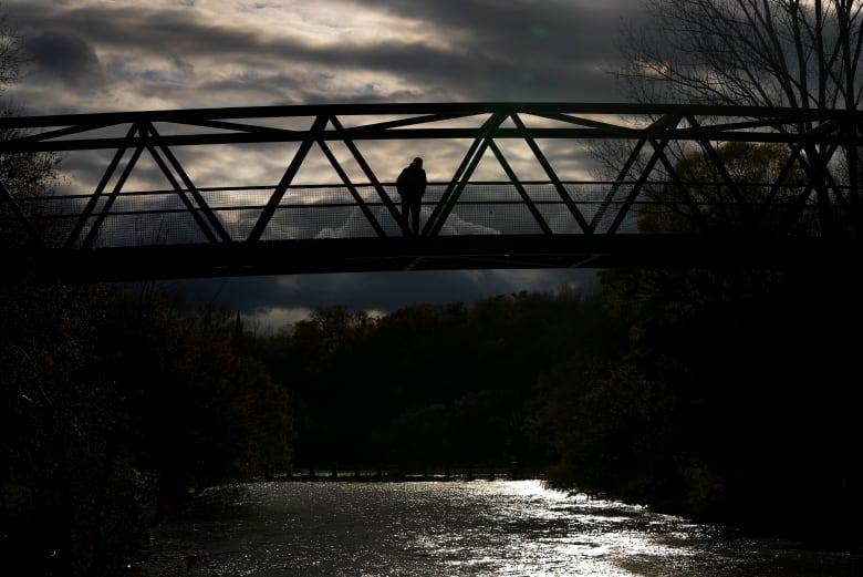 A person walks across a pedestrian bridge over the Credit River in Mississauga, Ont.