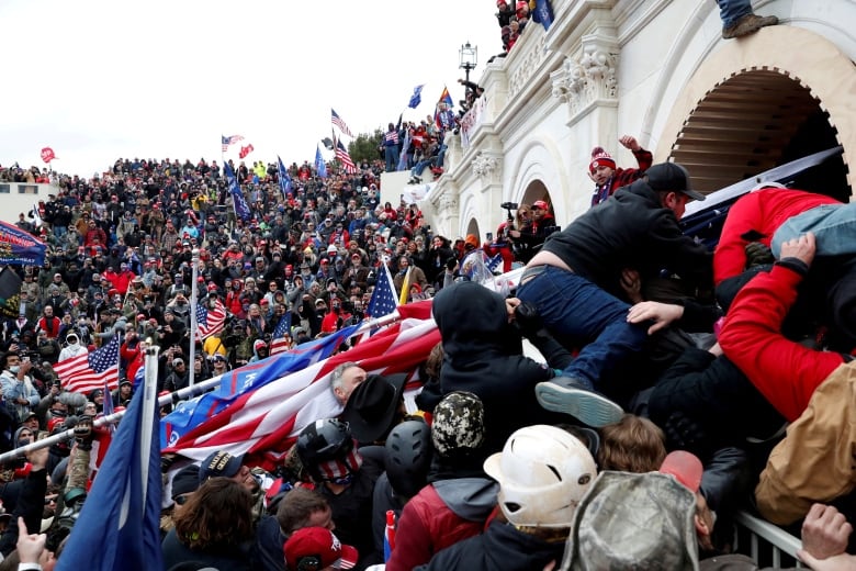 A mob smashes through an opening into the US Capitol