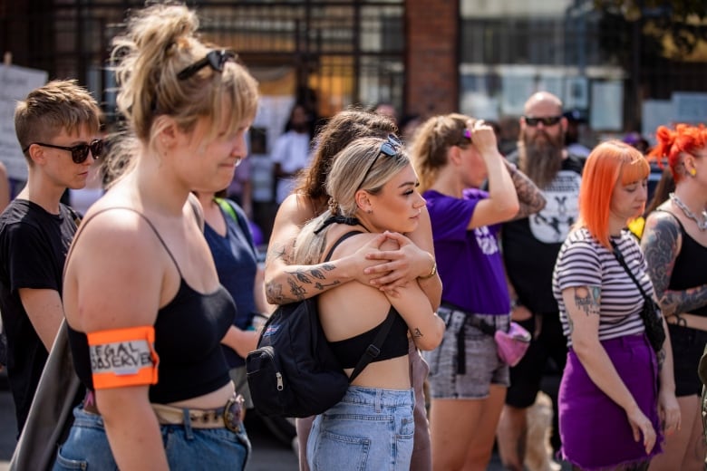 People embrace and grimace at a rally.