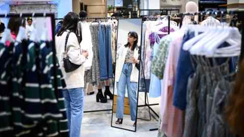 A woman browses through clothes displayed at a Shein pop-up store in Paris