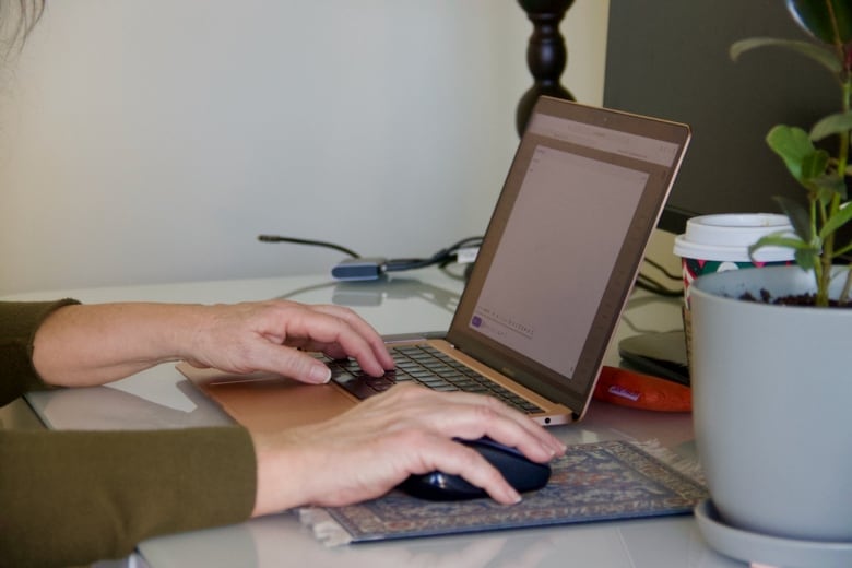 A hand can be seen typing an email on a laptop. 