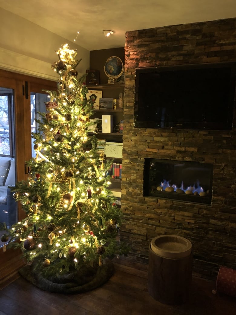 An eight-foot Christmas tree trimmed with brown and gold ribbons and lit with bright yellow lights.  