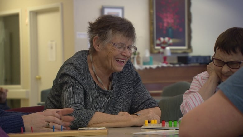 A woman laughs at a table.