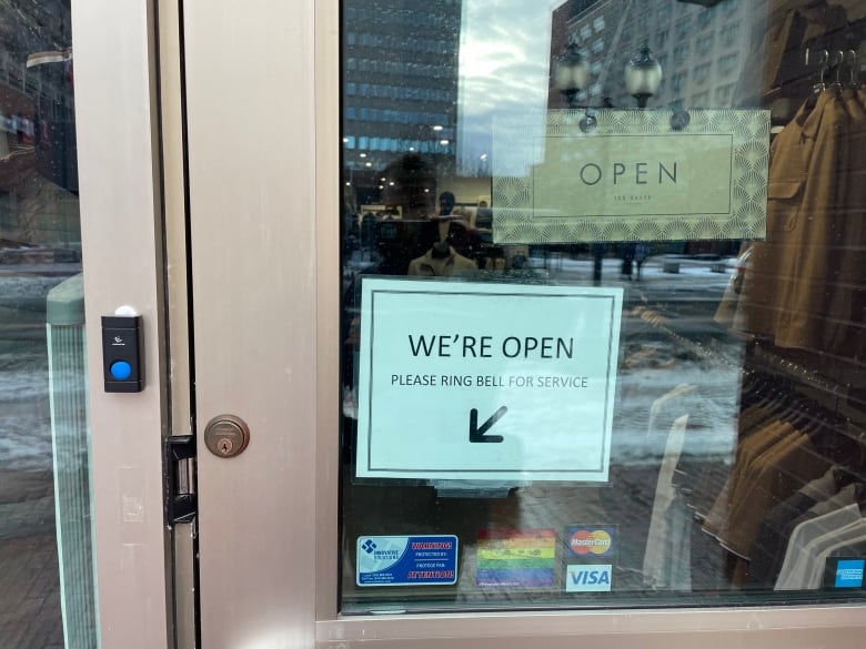 Sign that reads "We're open. Please ring bell for service." With an arrow 