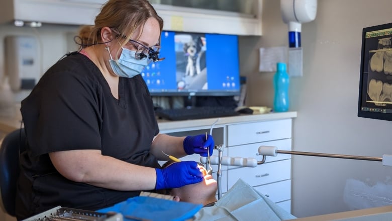 A dentist works on a patient reclined on a seat.