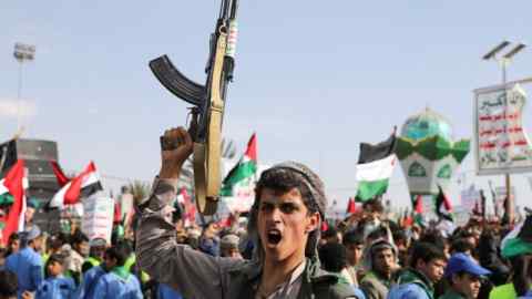 A man holds up a gun, as Houthi supporters rally to commemorate ten Houthi fighters killed by the U.S. Navy in the Red Sea, in Sanaa, Yemen January 5, 2024