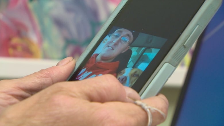 Bev Cadham holds her cell phone in her hands. There's a photo of her son Shaymus displayed on the phone. 