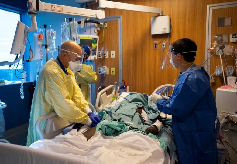 A doctor is seen treating a patient in a hospital bed.