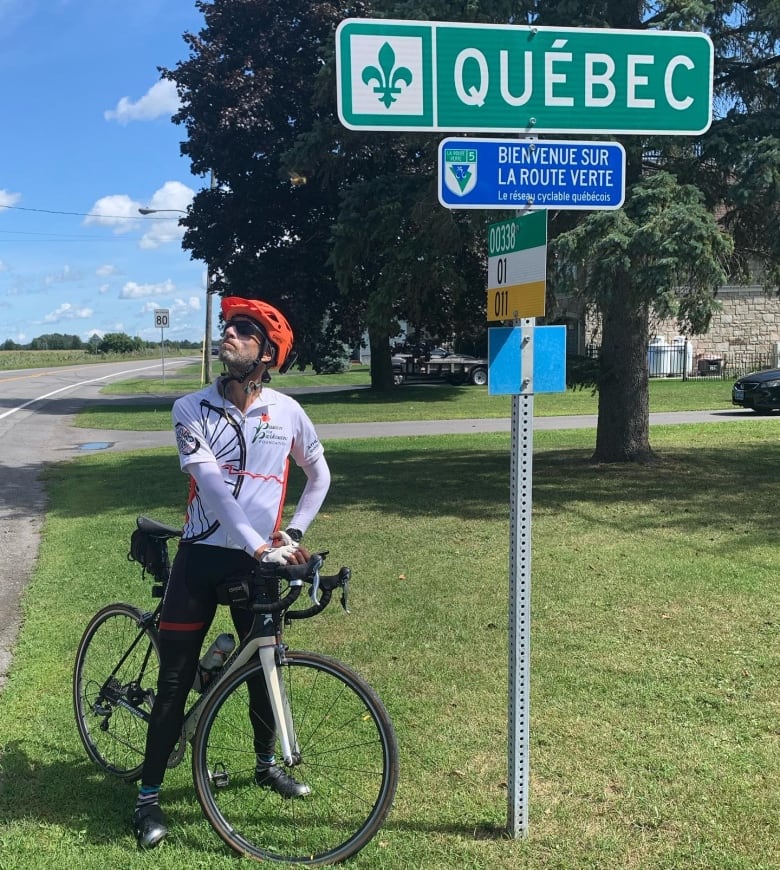 Man on bicycle beside sign that says "Quebec"