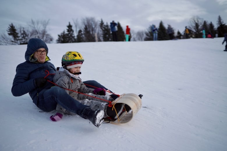 Man and his daughter sledding.