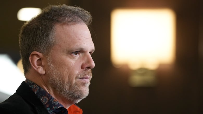 A man listens to a question from reporters.