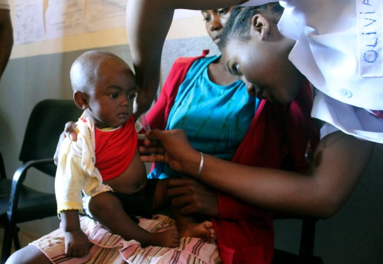 In this photo taken on Thursday, March 21, 2019, a volunteer nurse examines 6-moth-old Sarobidy, who is infected with measles, while her mother Nifaliana Razaijafisoa looks on, at a healthcare centre in Larintsena, Madagascar. 